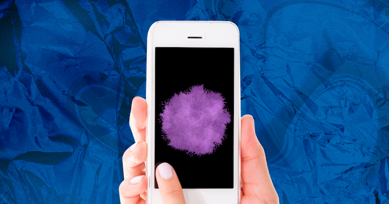 A hand holds a smartphone with a fuzzy purple ball on the screen against a blue background.