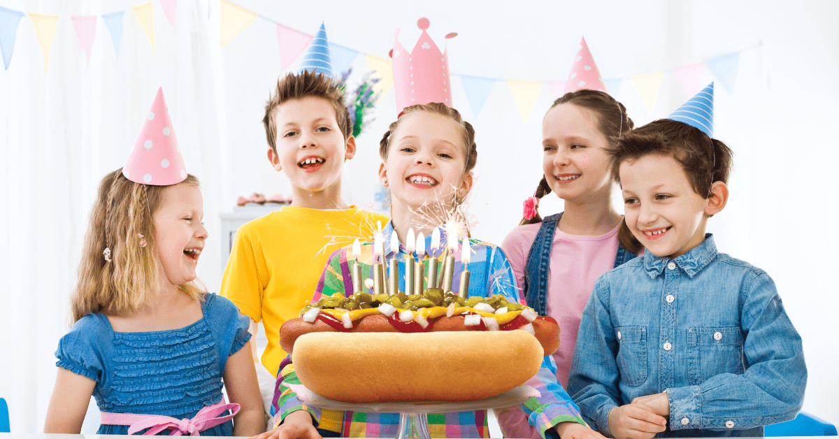 A children’s birthday party with kids gathered around a hot dog with candles in it.