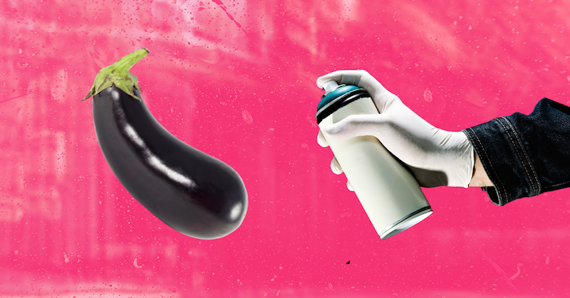 A white-gloved hand sprays an eggplant with an aerosol can against a pink background.